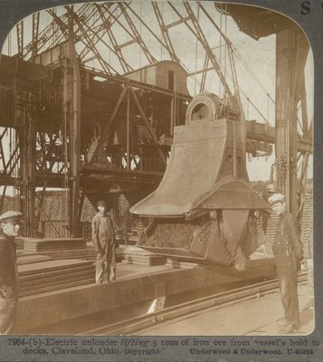 Electric unloader lifting 5 tons of iron ore from vessel's hold to docks, Cleveland, Ohio